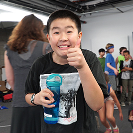 A student holding a water bottle gives a thumbs up.
