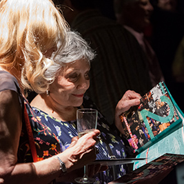 One person peers over the shoulder of another as they look at a theatre brochure.