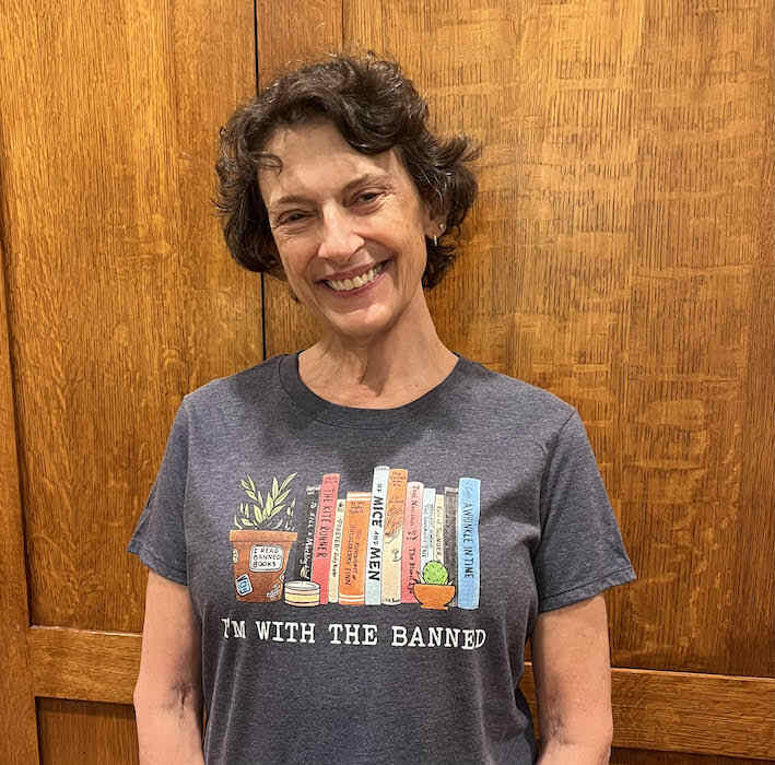 The author, Miranda Johnson-Haddad wearing a gray t-shirt with an image of book spines and the text "I'm with the Banned"